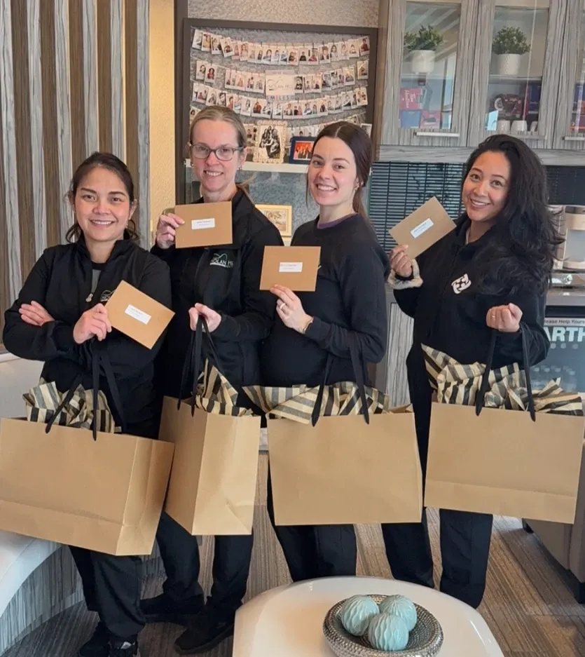 Four team members holding gift bags and envelopes in the reception area